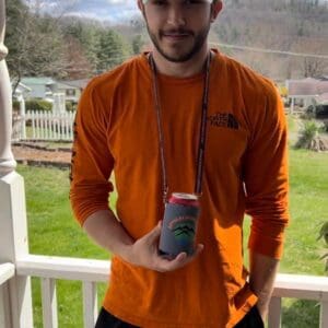 A man holding two drinks on the porch.