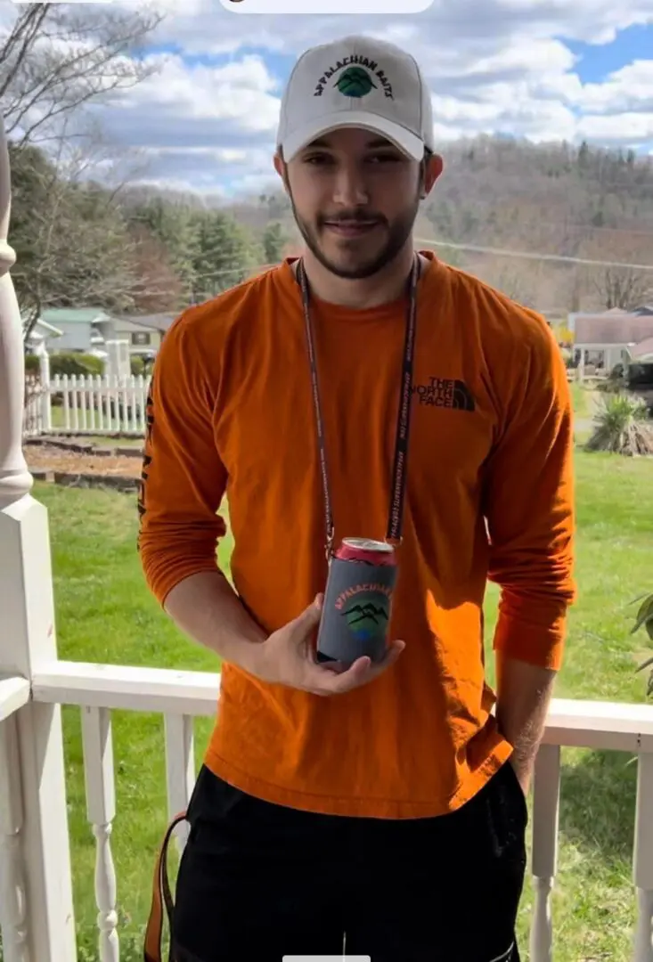 A man holding two drinks on the porch.