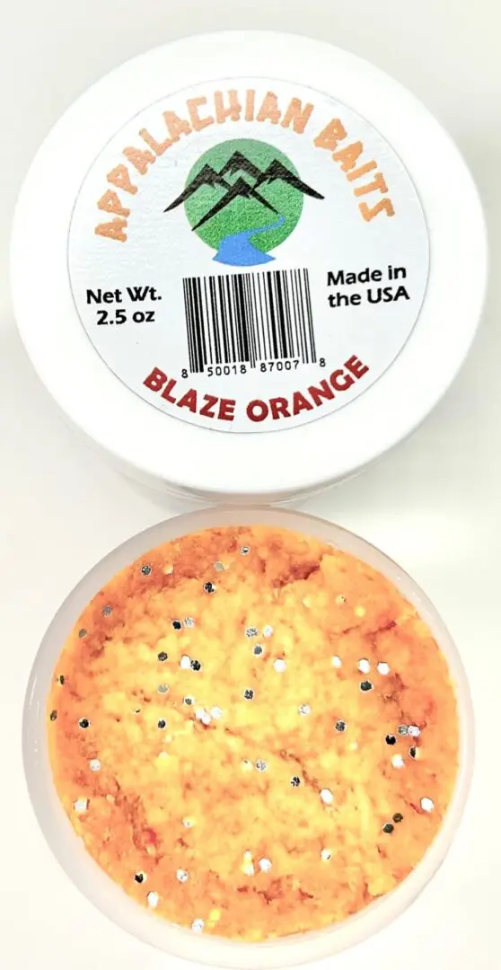 A container of orange ice cream with black and white sprinkles.