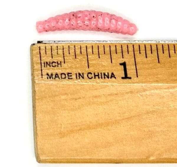 A wooden ruler with a pink crochet caterpillar on it.