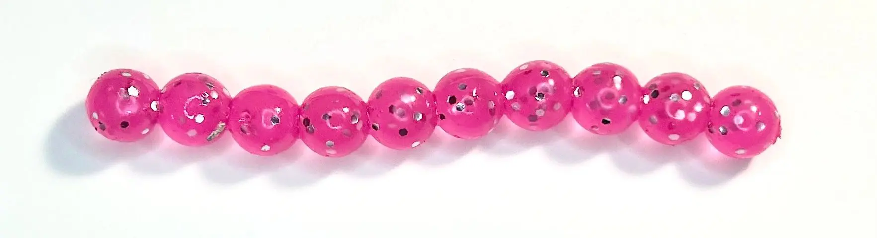 A pink bead with black and white polka dots.