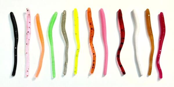 A group of different colored plastic worms on a white surface.