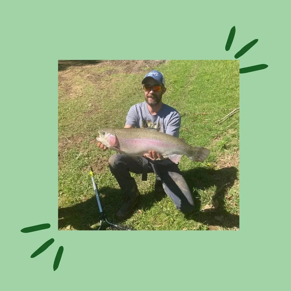 A man holding a fish while sitting on the ground.