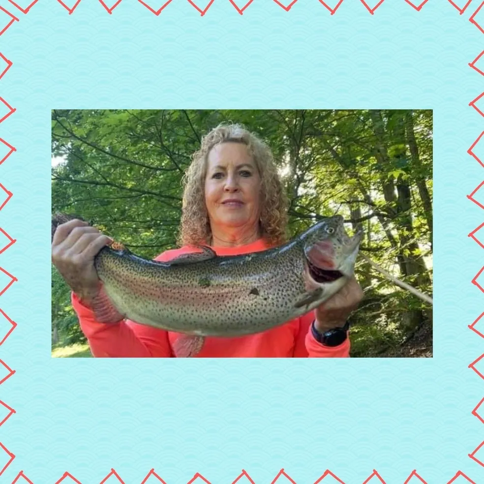 A woman holding up a fish in front of her face.