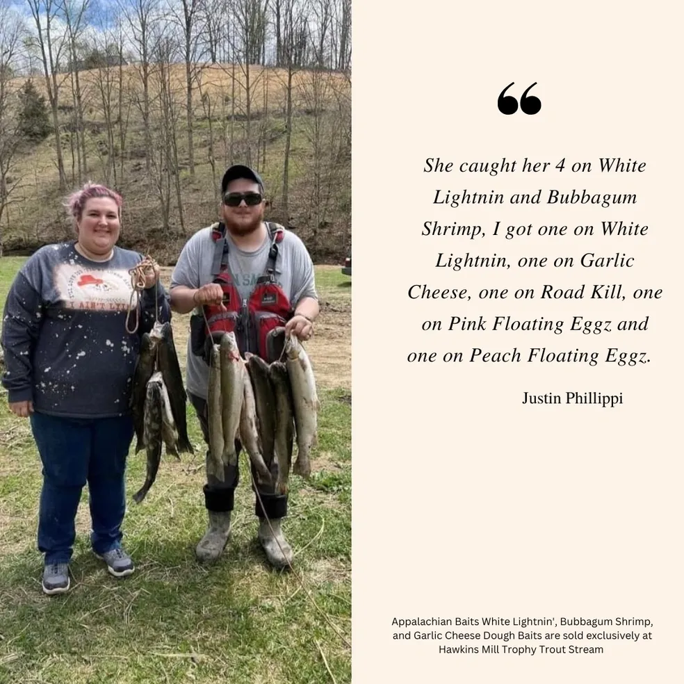 Two people holding fish in a field.